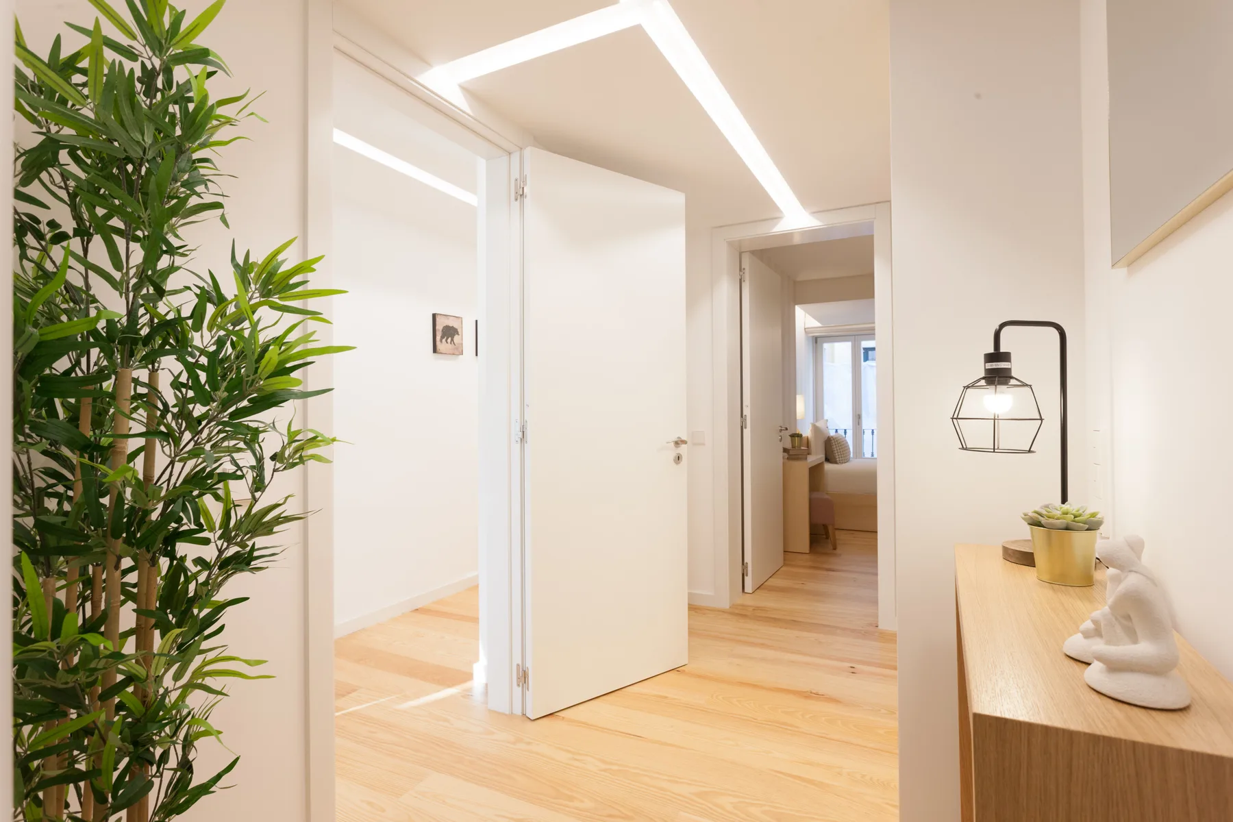 A bright hallway with light wood flooring and an open doorway.