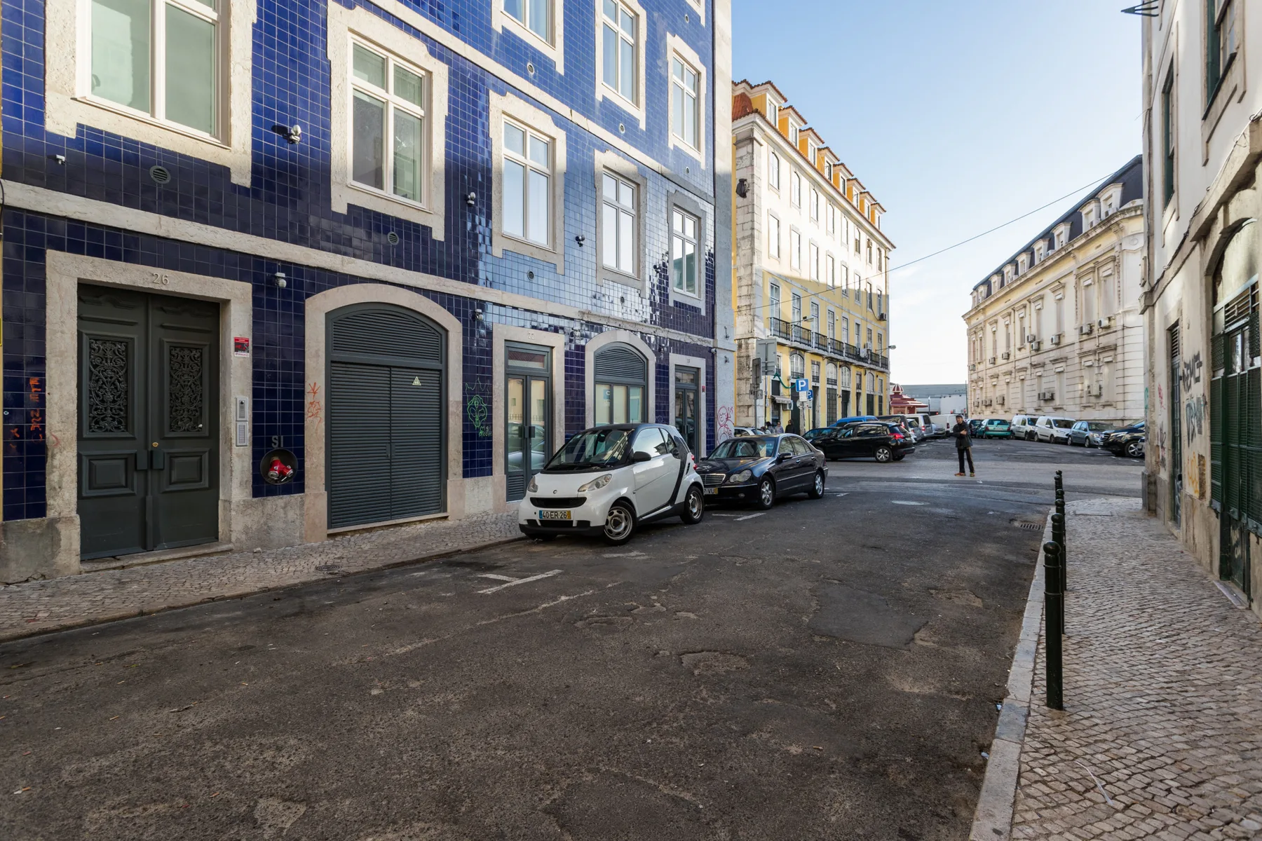 A narrow city street lined with tiled buildings and parked cars.