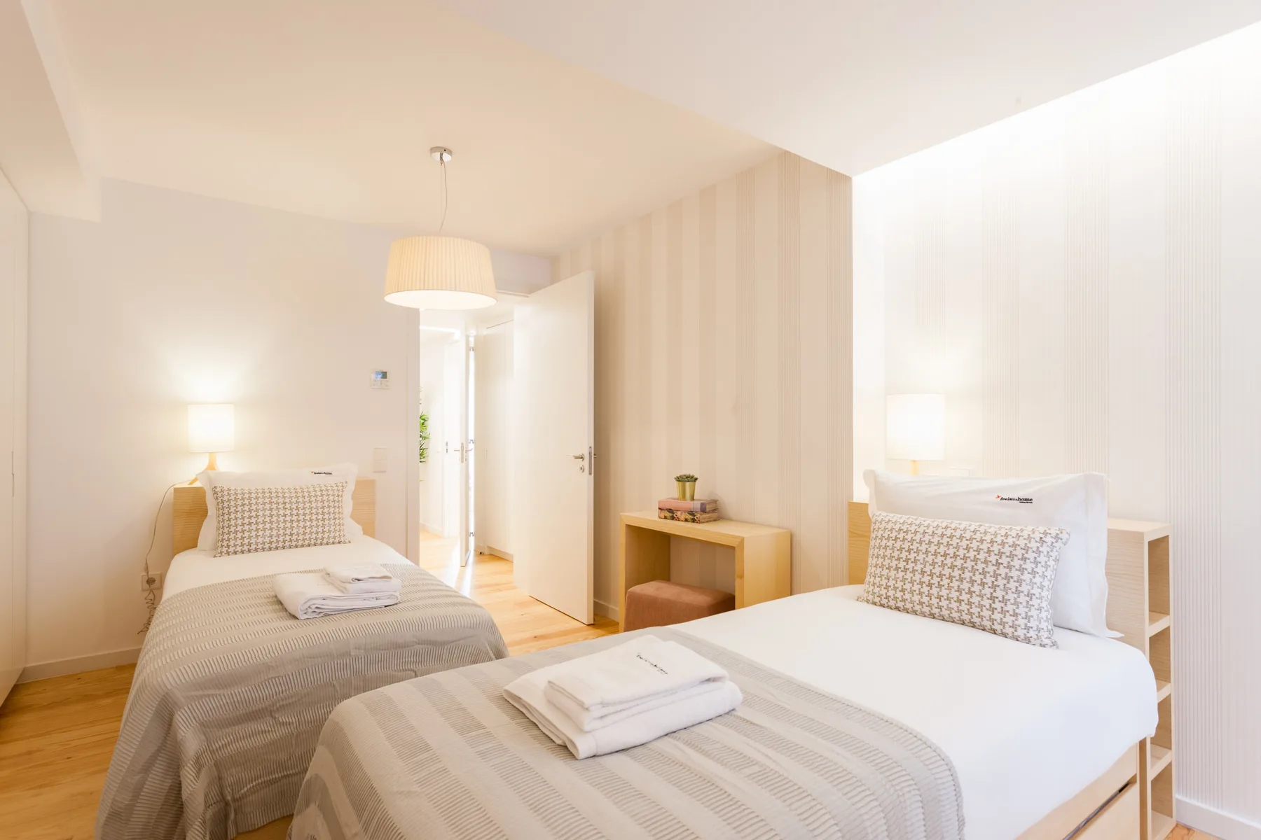 A bright bedroom with two beds and folded towels.