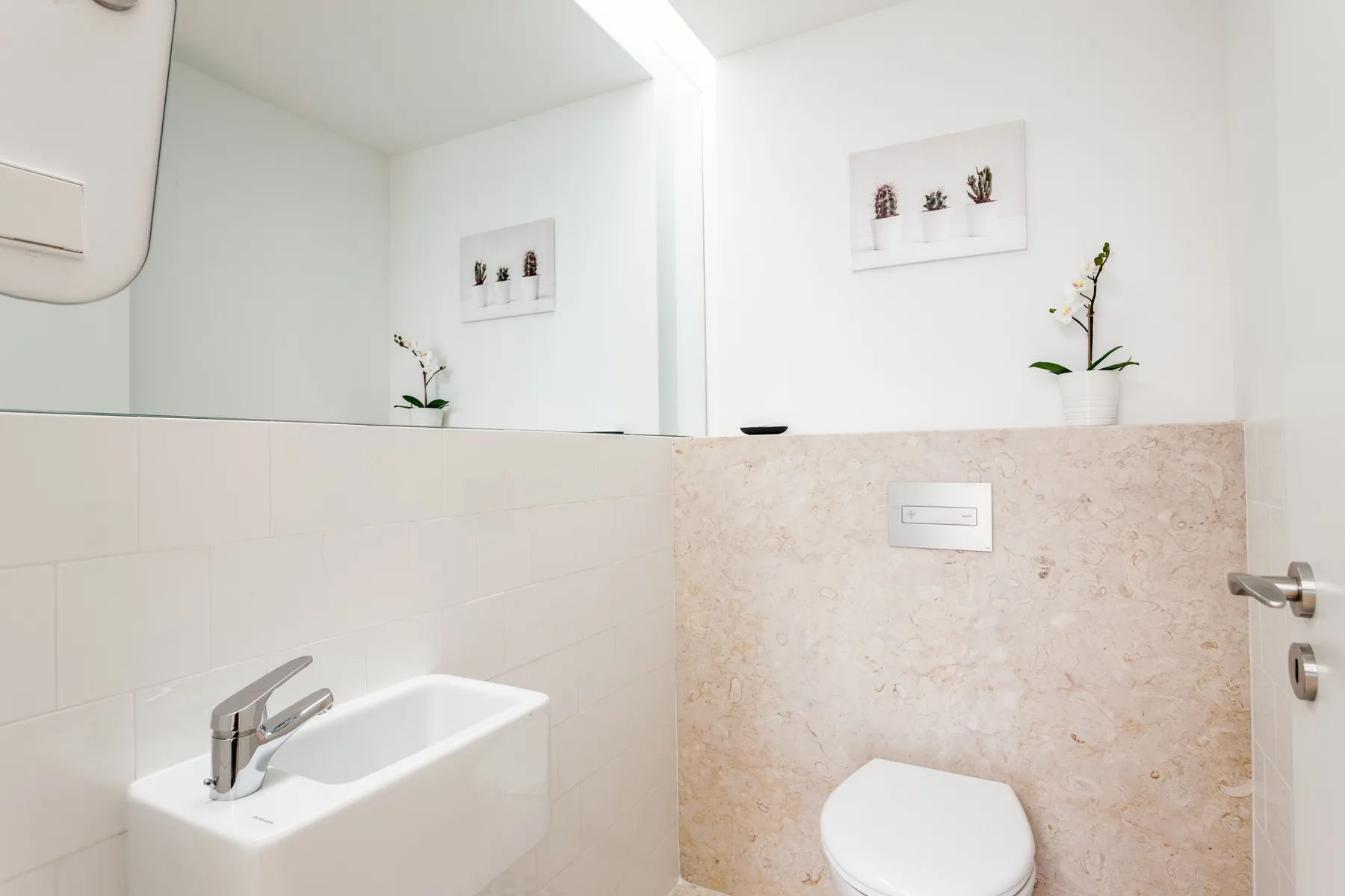 A bright bathroom with a sink, toilet, and large wall mirror.