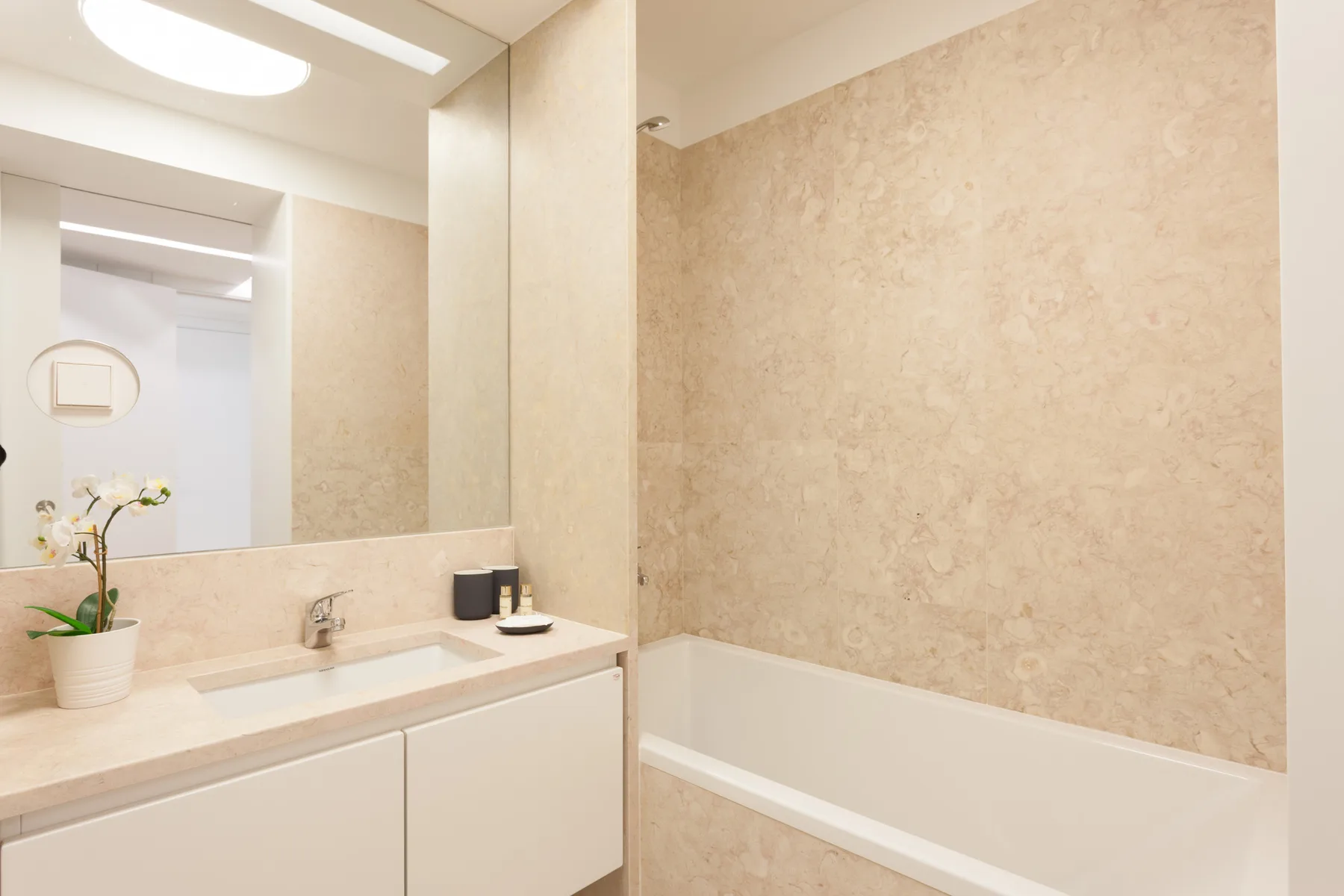 A bathroom with a vanity, mirror, and bathtub.