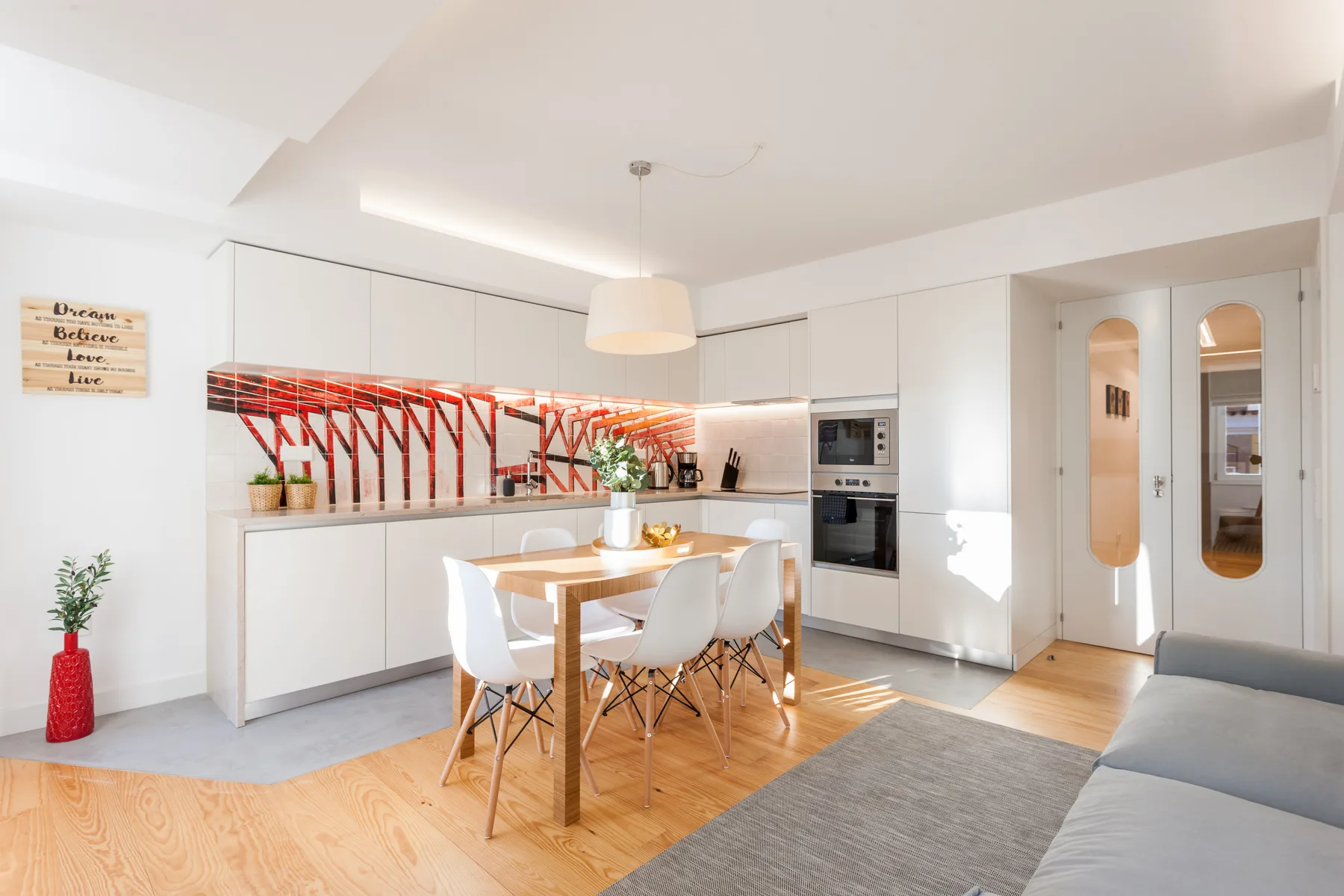 A bright kitchen and dining area with white cabinets and a wooden table.