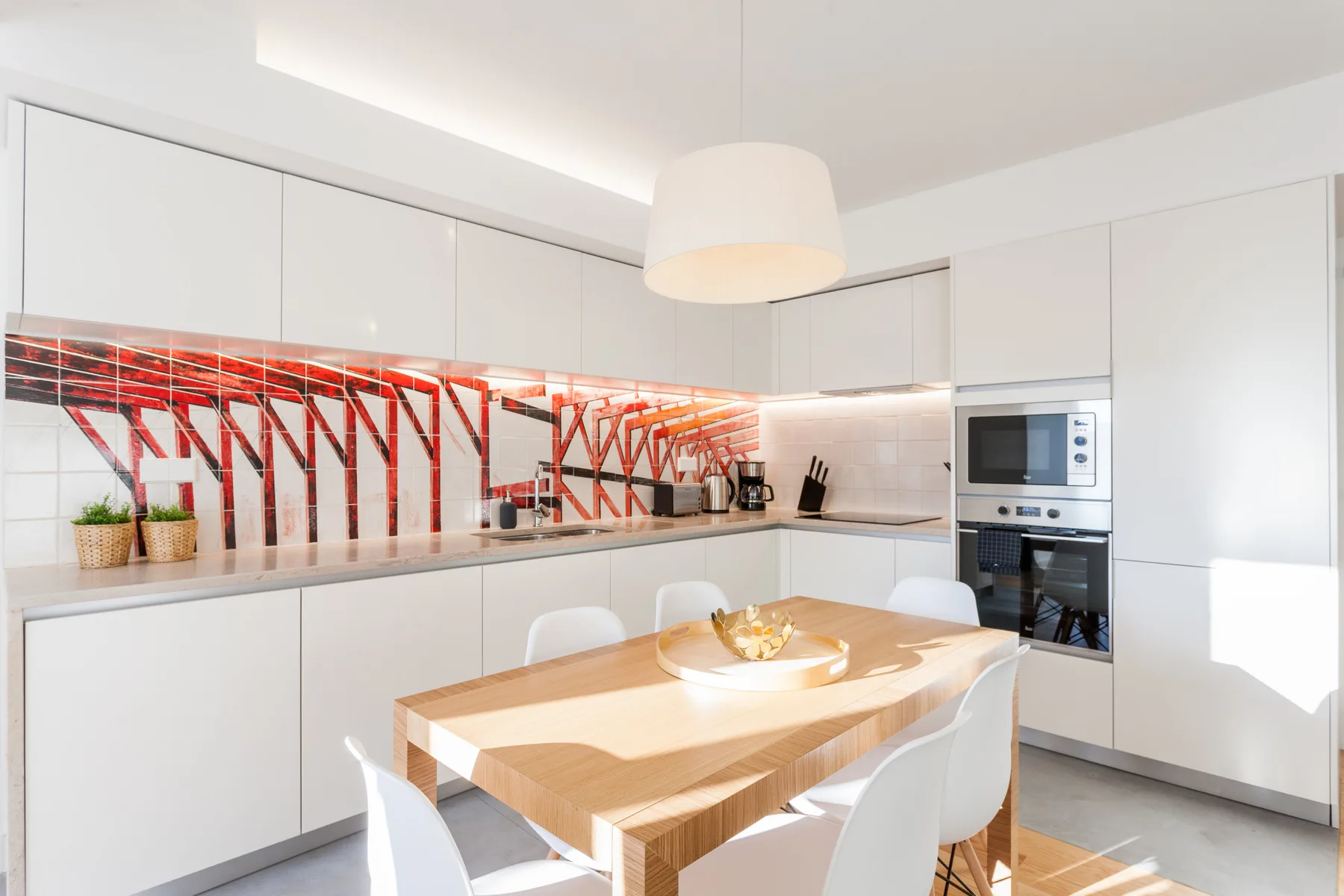 A bright kitchen and dining area with white cabinets and a wooden table.