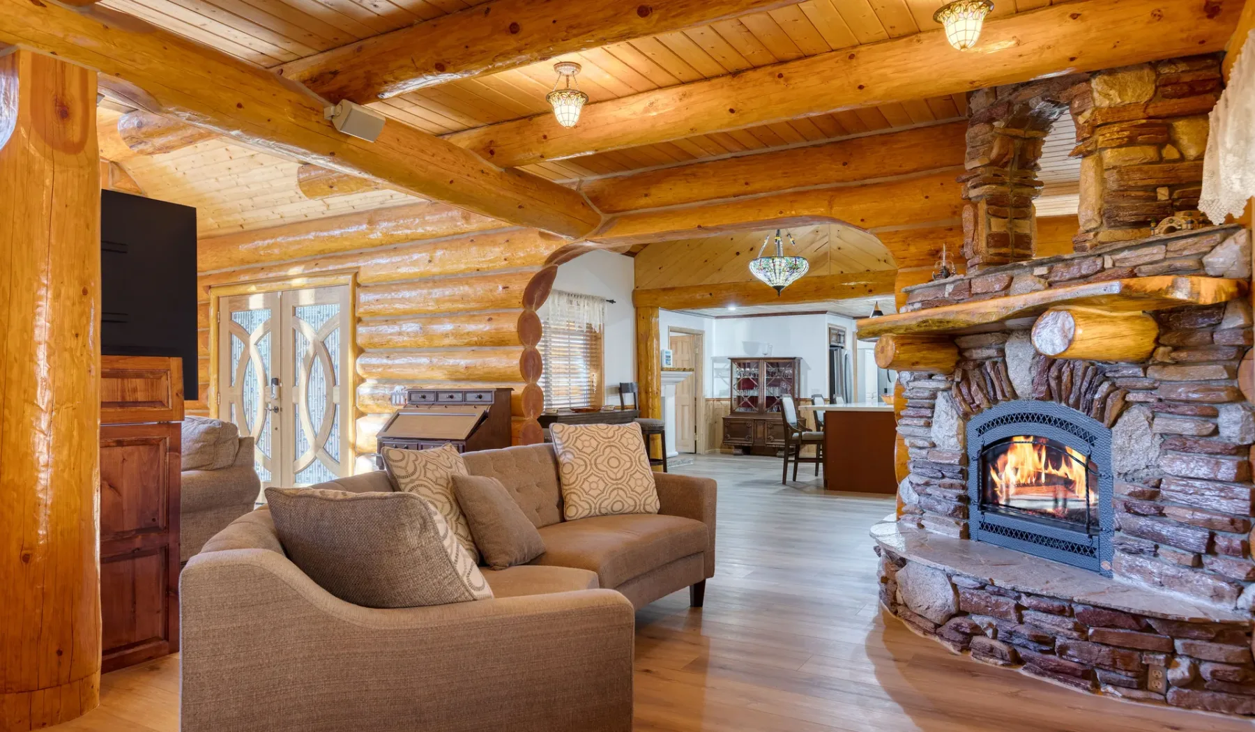 A log cabin living room with seating and a stone fireplace.