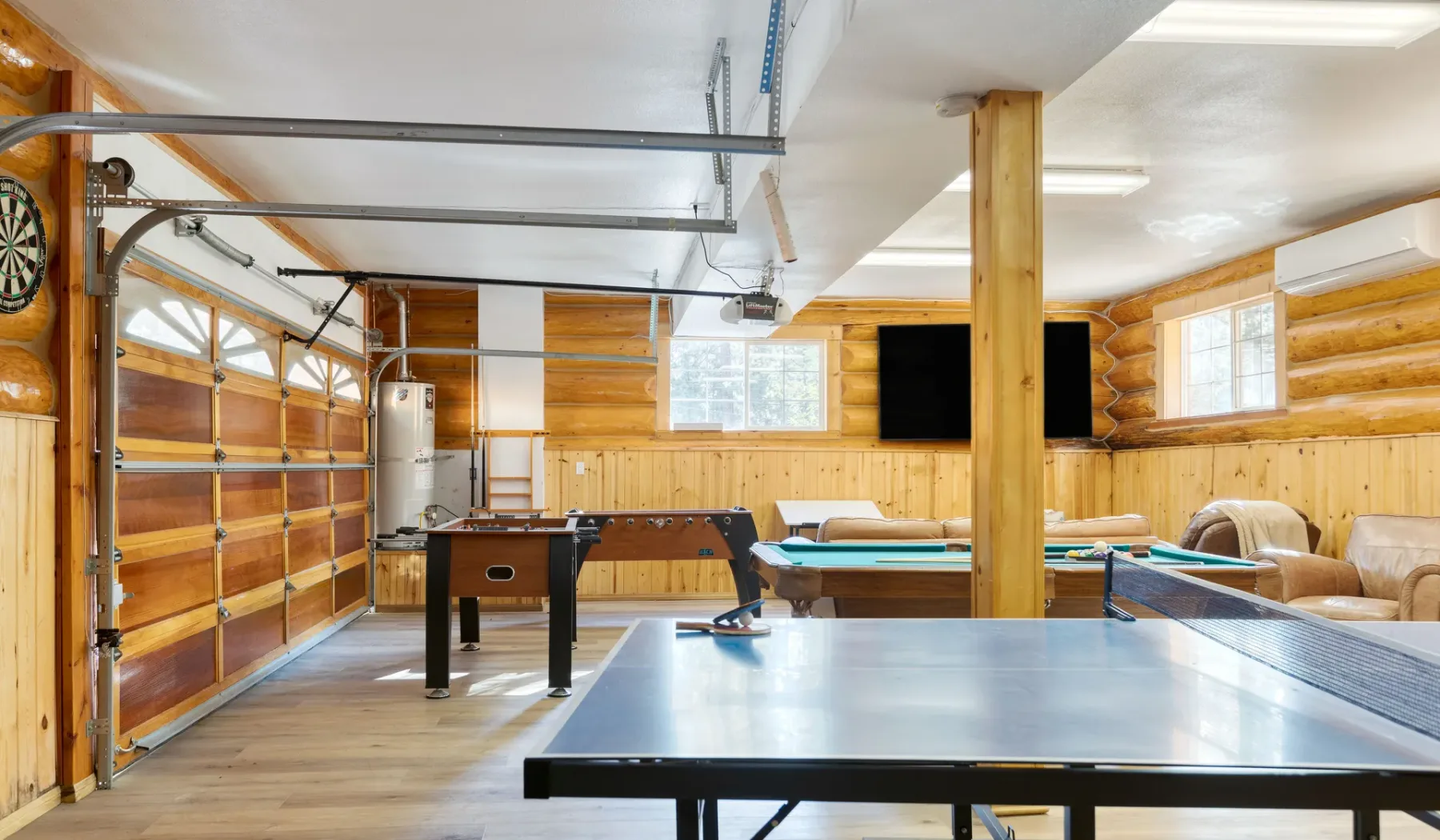 A recreation room with a ping-pong table, pool table, and dartboard.