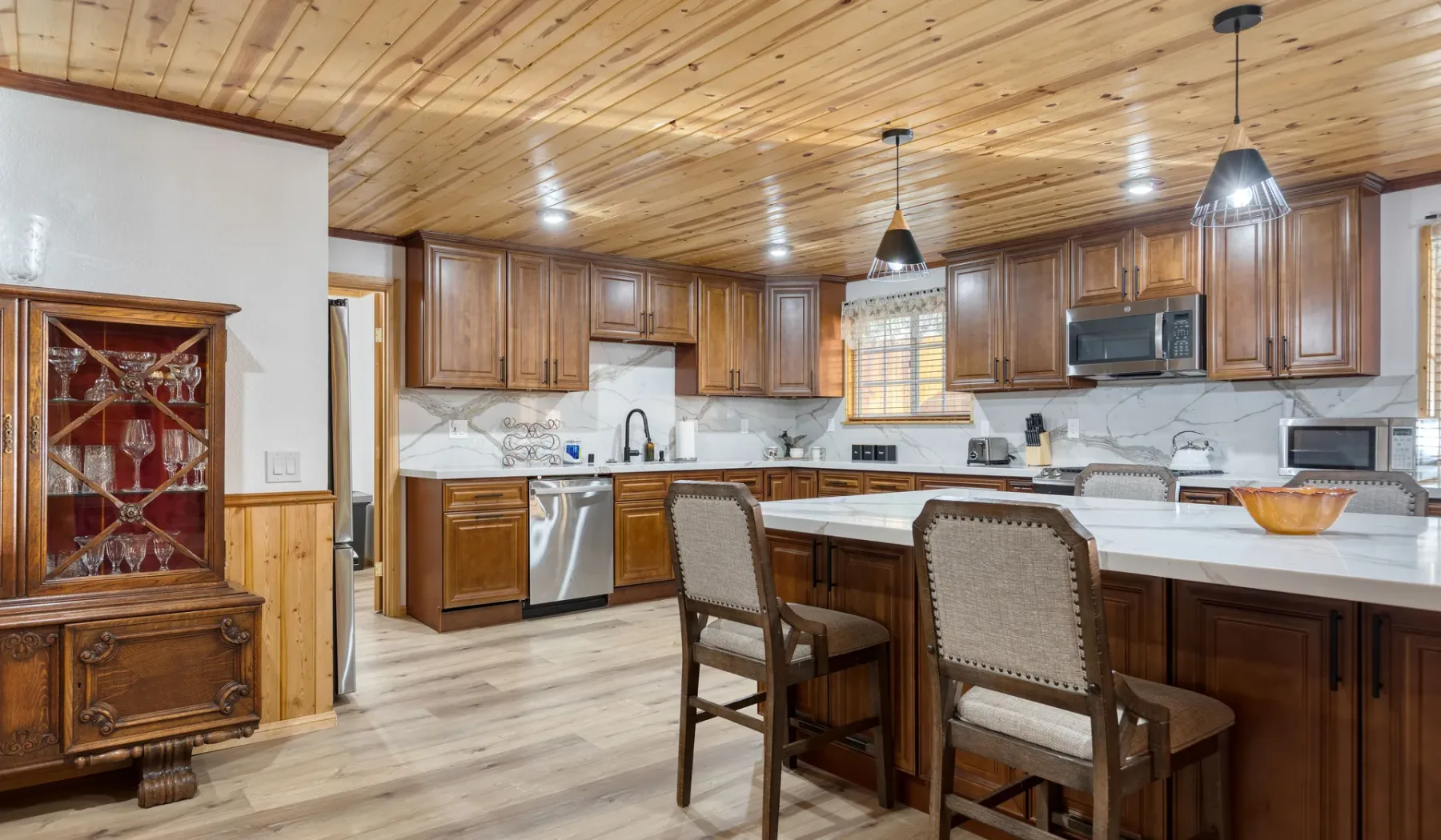 A spacious kitchen with a central island, wooden cabinetry, and dining seating.