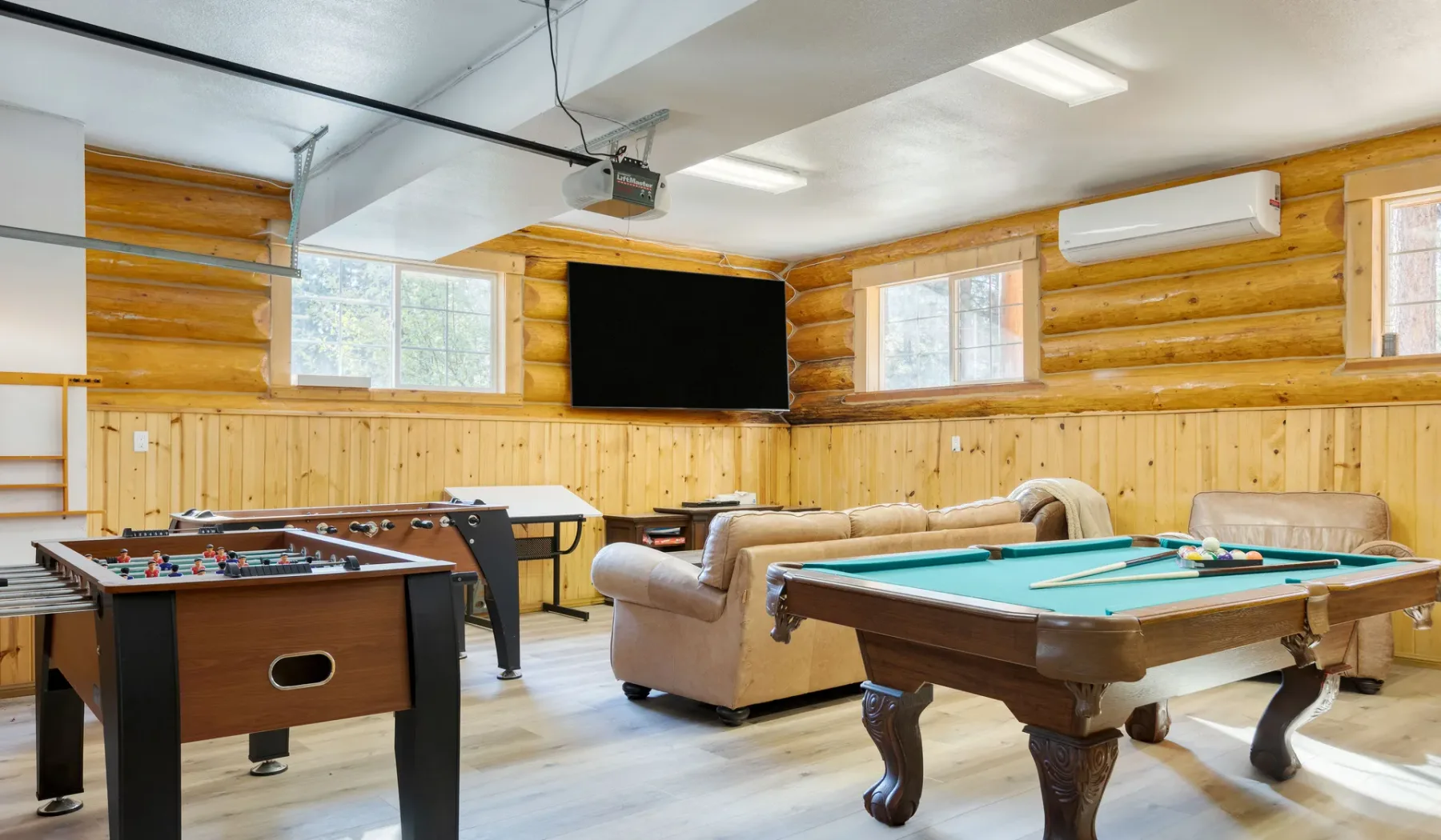A recreation room with a pool table, foosball table, and seating.