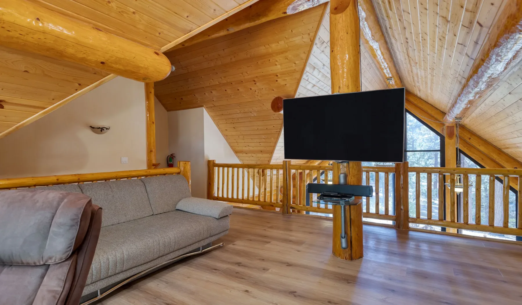 A wood-paneled loft living area with a sofa and television.