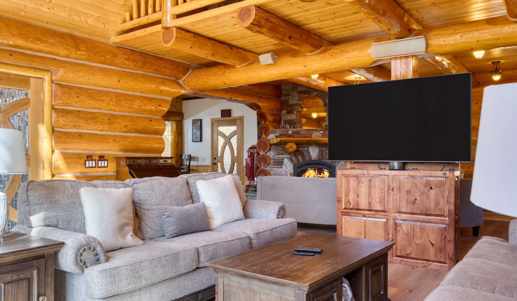 A log-cabin living room with seating, a coffee table, and a television.