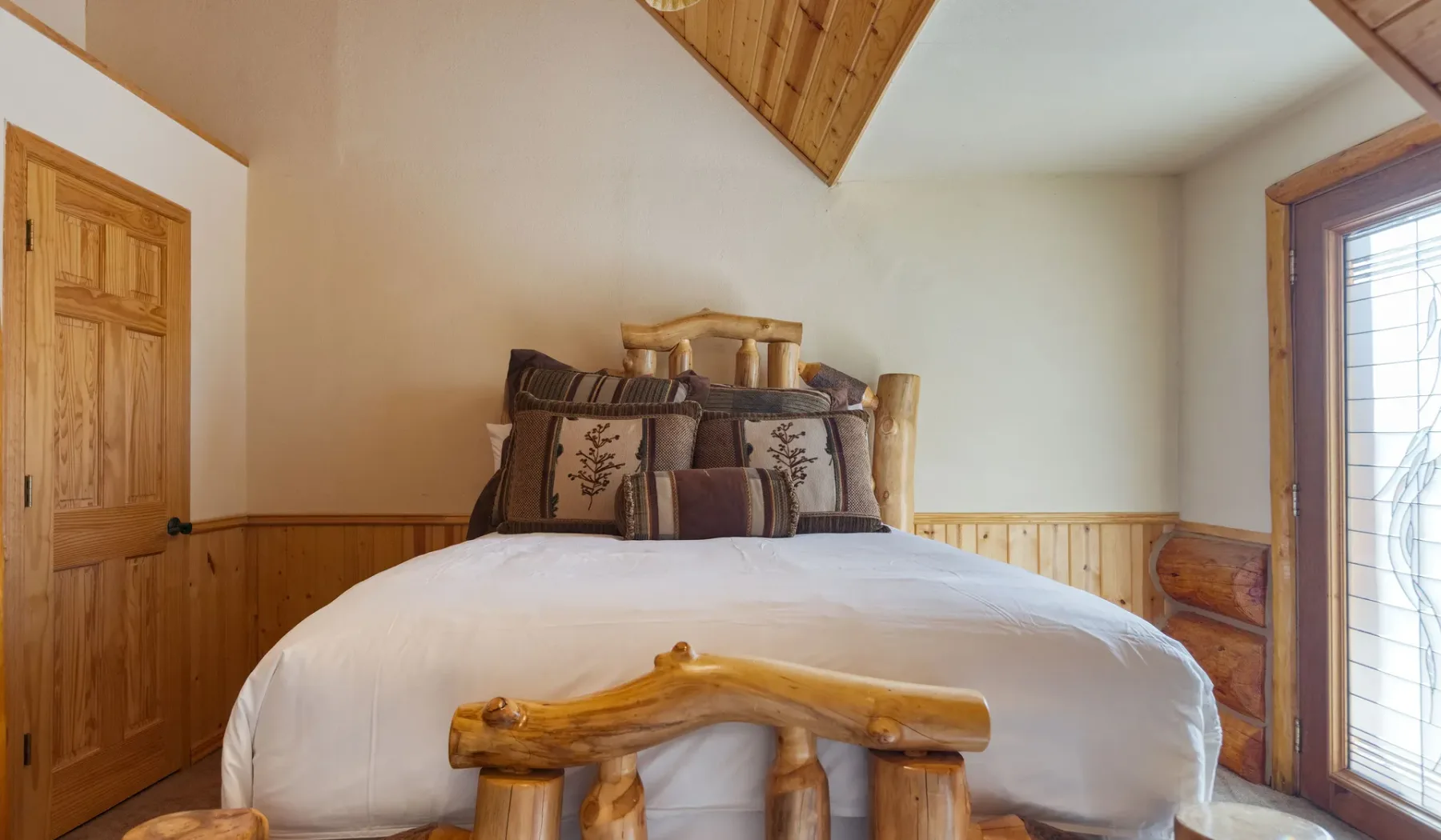A bedroom with a bed and wood furnishings.