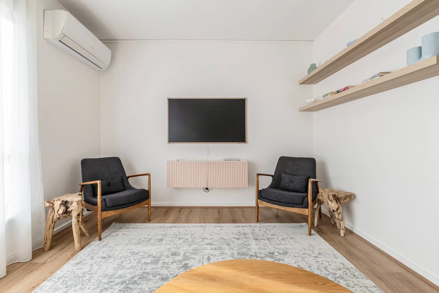 Enjoy evenings with your favourite shows on the TV, set between mid-century chairs and natural wood details under soft ambient light.