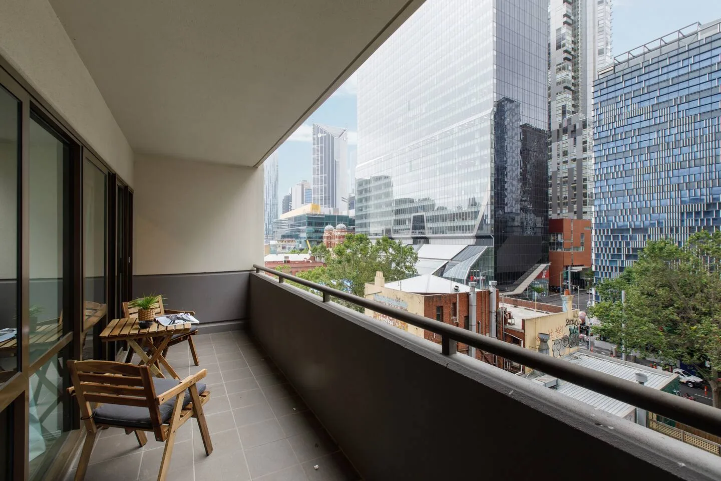 A balcony with outdoor seating overlooks nearby city buildings.