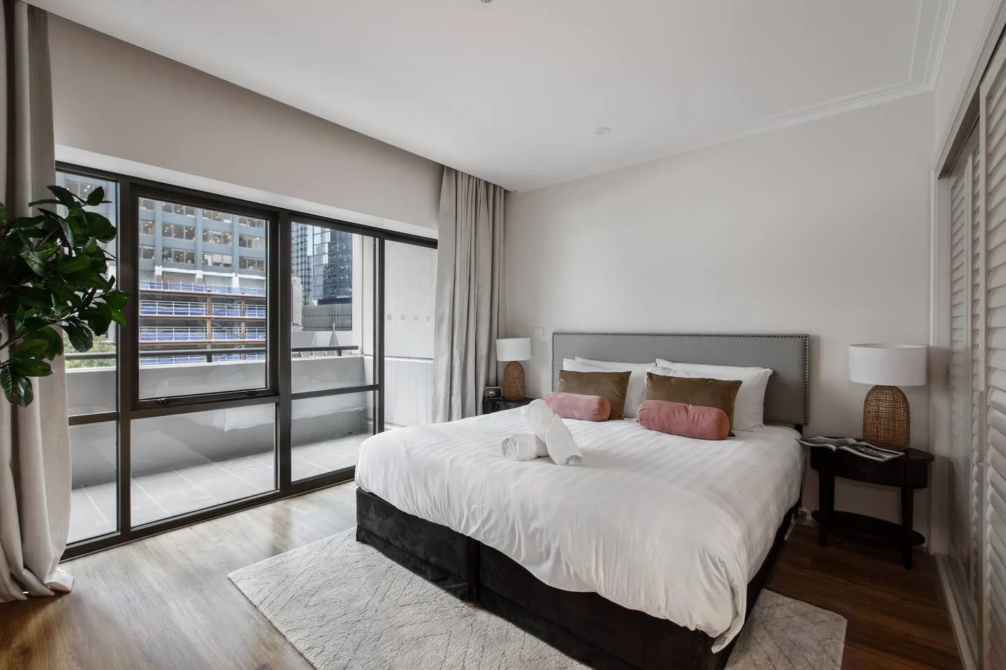 A bedroom with a large bed, bedside tables, and wide windows.