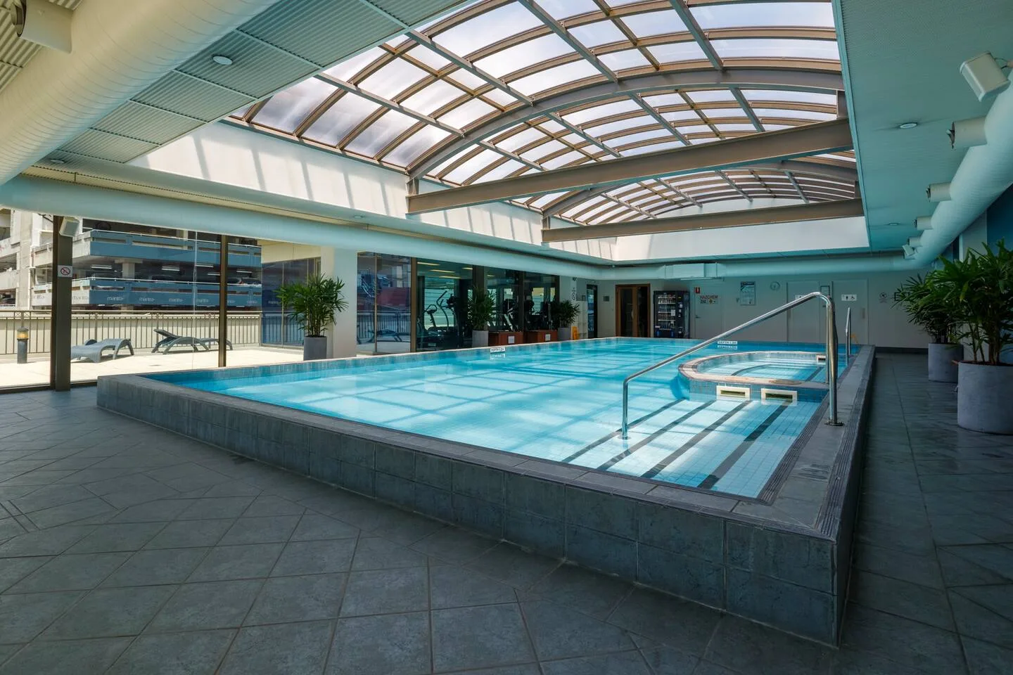 An indoor swimming pool beneath a large glass roof.
