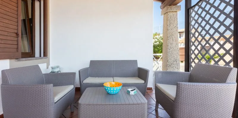 A covered patio seating area with cushioned outdoor furniture and a low table.