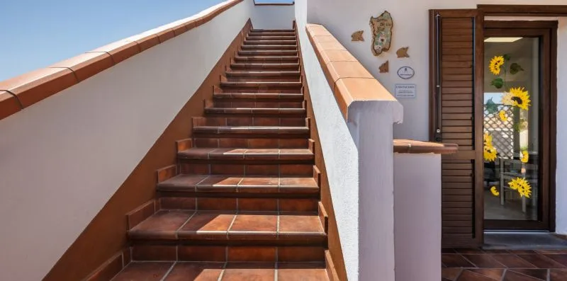 A tiled staircase rises beside a doorway decorated with sunflowers.