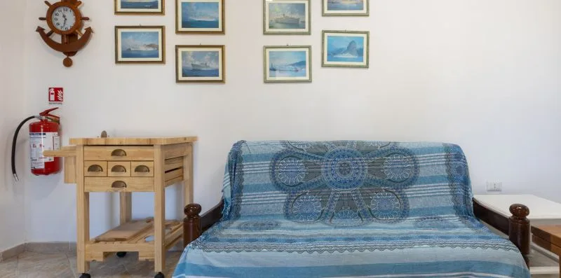 A sitting room with blue patterned seating beneath framed pictures.