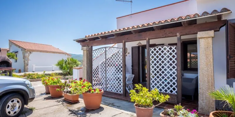 A patio with potted flowers sits beside a building with lattice screens.