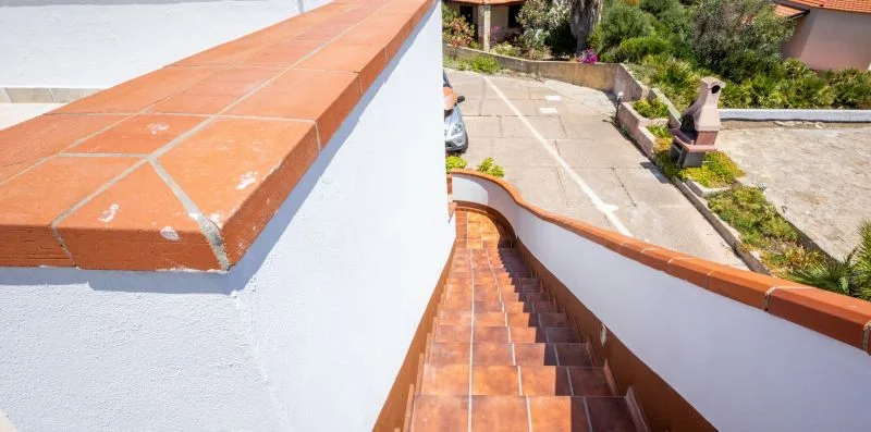 Outdoor steps descend beside a white wall toward a paved courtyard.