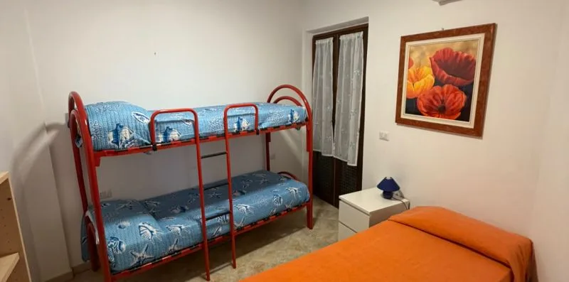 A bedroom with red metal bunk beds and an orange bed.