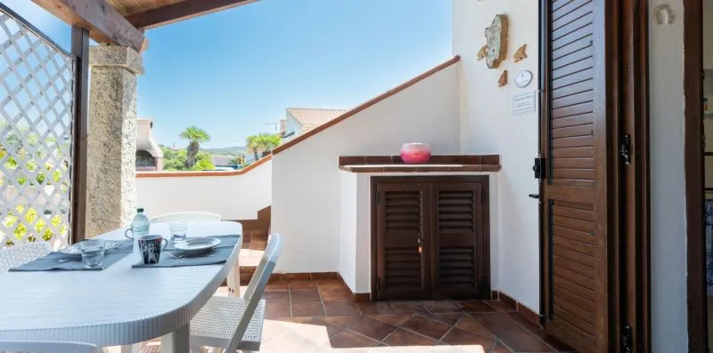 A covered patio dining area with a table beside a shuttered cabinet.