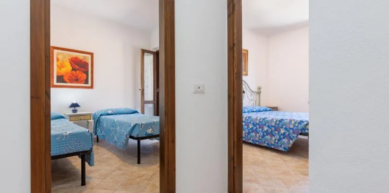 A bedroom with blue bedding is visible through two doorways.