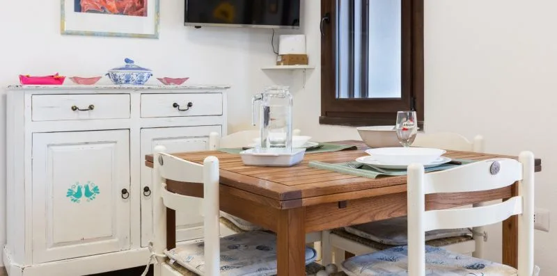 A dining area with a wooden table, white chairs, and a window.