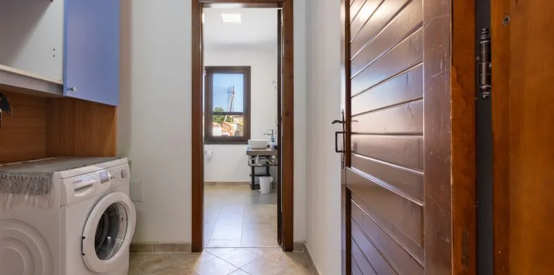 A tiled hallway with a washing machine beside an open doorway.