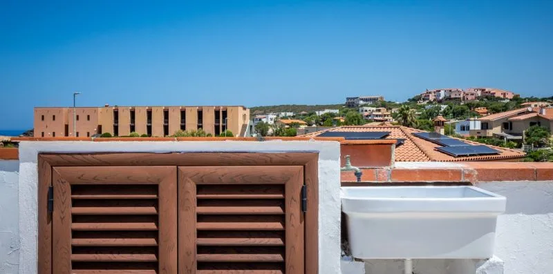 A rooftop scene with brown louvered shutters and nearby terracotta roofs.