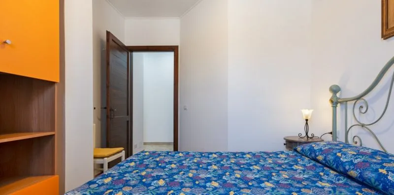 A bedroom with a colorful patterned bedspread and an open doorway.