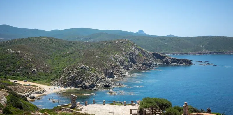 A coastal landscape with rocky hills surrounding a blue bay.