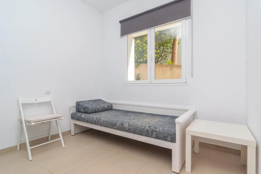 A simple bedroom with a single bed beneath a window.