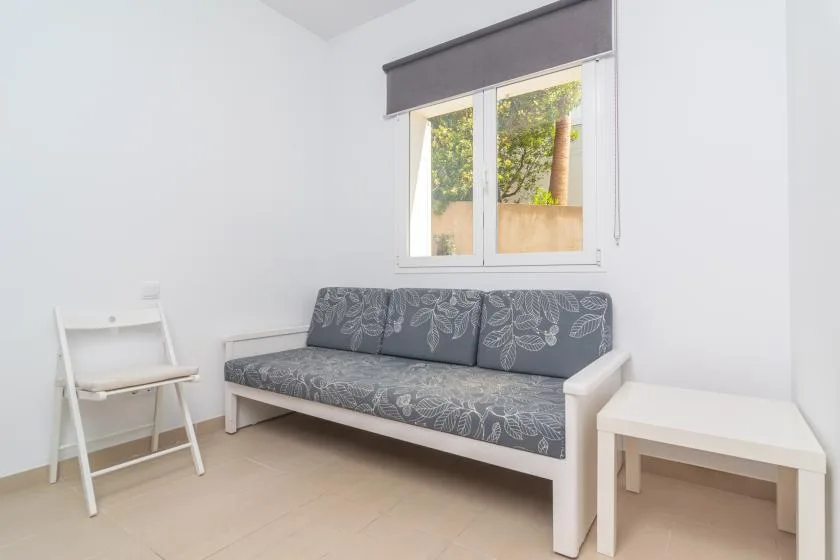 A bright living room with a patterned sofa beneath a window.