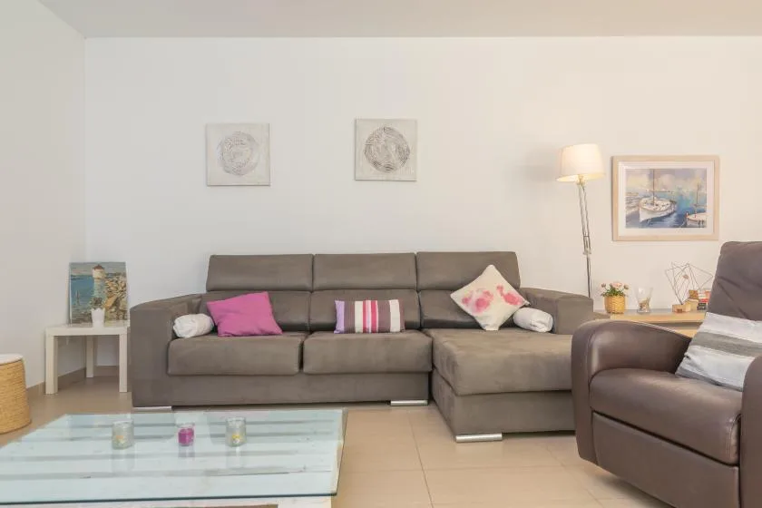 A living room with sectional seating, a glass coffee table, and a floor lamp.