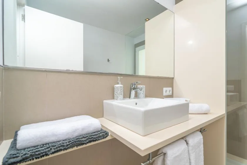 A bathroom vanity with a rectangular sink, mirror, and folded towels.