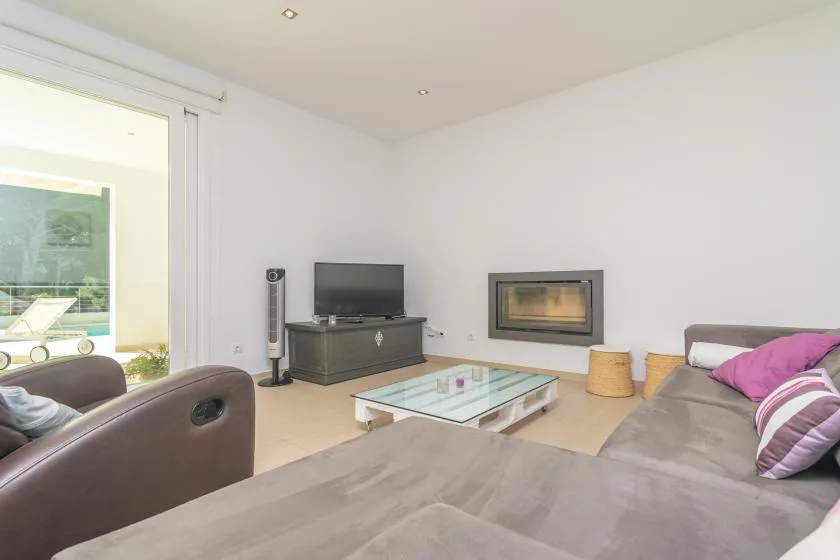 A bright living room with seating, a television, and a glass coffee table.