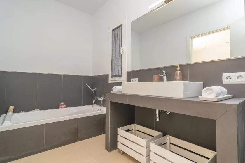 A bathroom with a bathtub and a wide vanity topped by a rectangular sink.