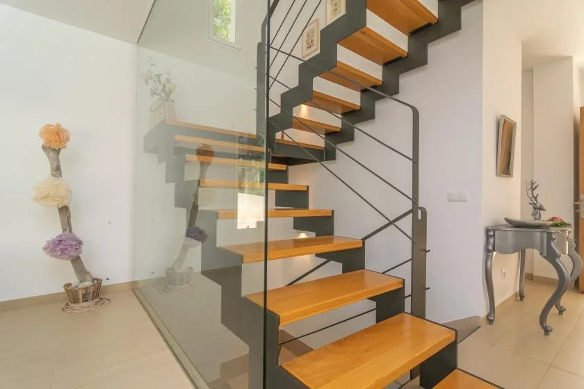 A modern interior staircase with wooden steps and a glass railing.