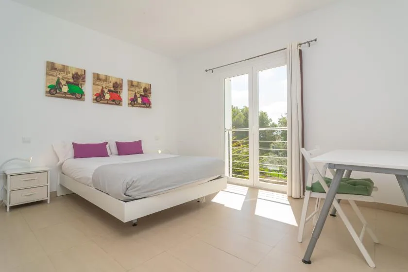 A bright bedroom with a bed and glass doors opening onto a balcony.