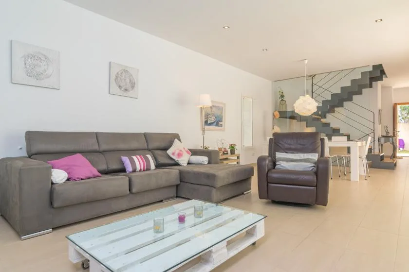 A modern living room with gray seating and a glass coffee table.