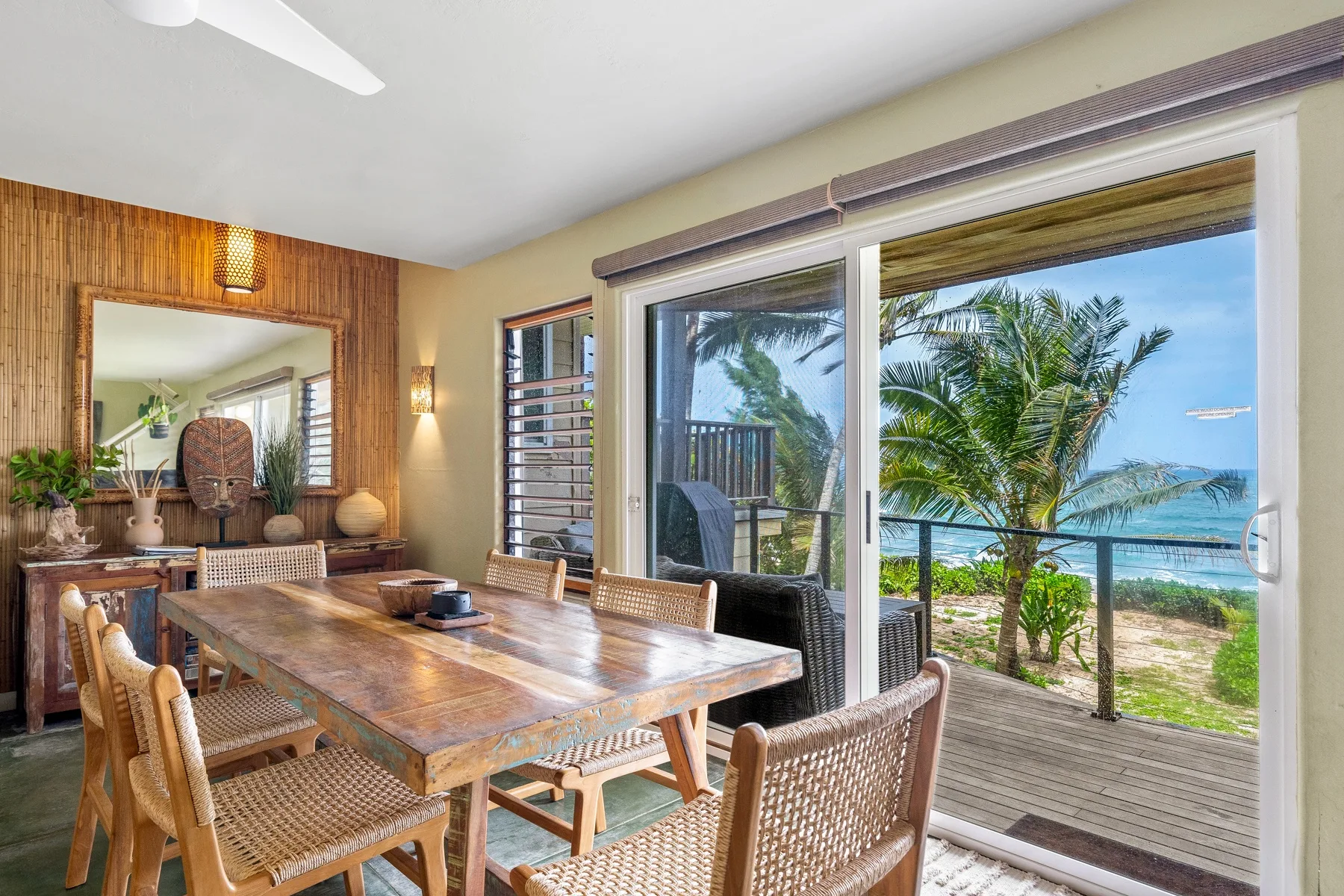 Un comedor con una mesa de madera y puertas corredizas de vidrio con vistas al agua.
