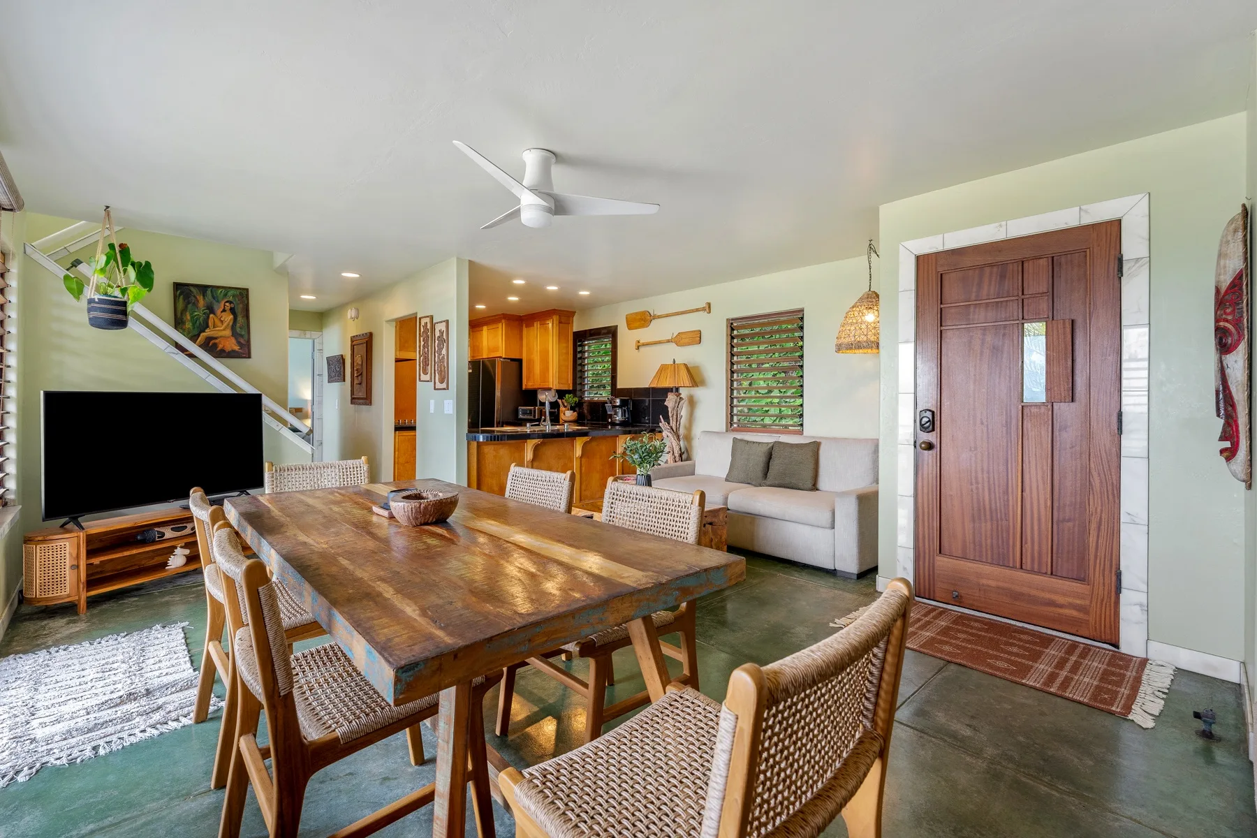 Zona de comedor y sala de estar con una mesa grande de madera y asientos.