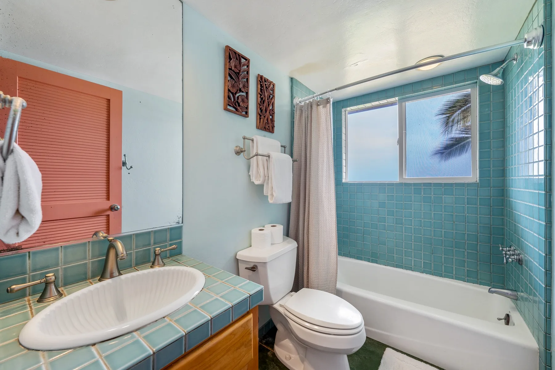 Un baño con lavabo de azulejos, inodoro y bañera junto a una ventana.