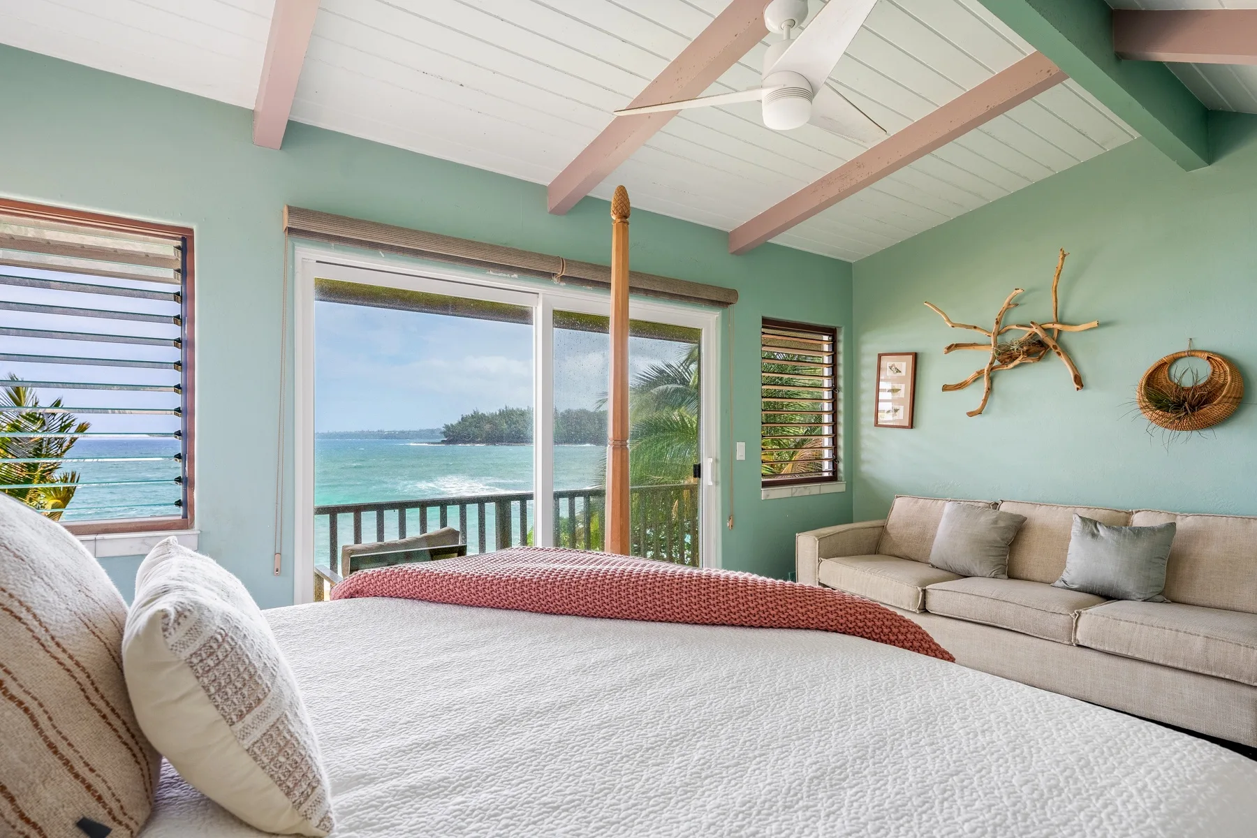 Un dormitorio con una cama grande, una zona de estar y vistas al mar por las ventanas.