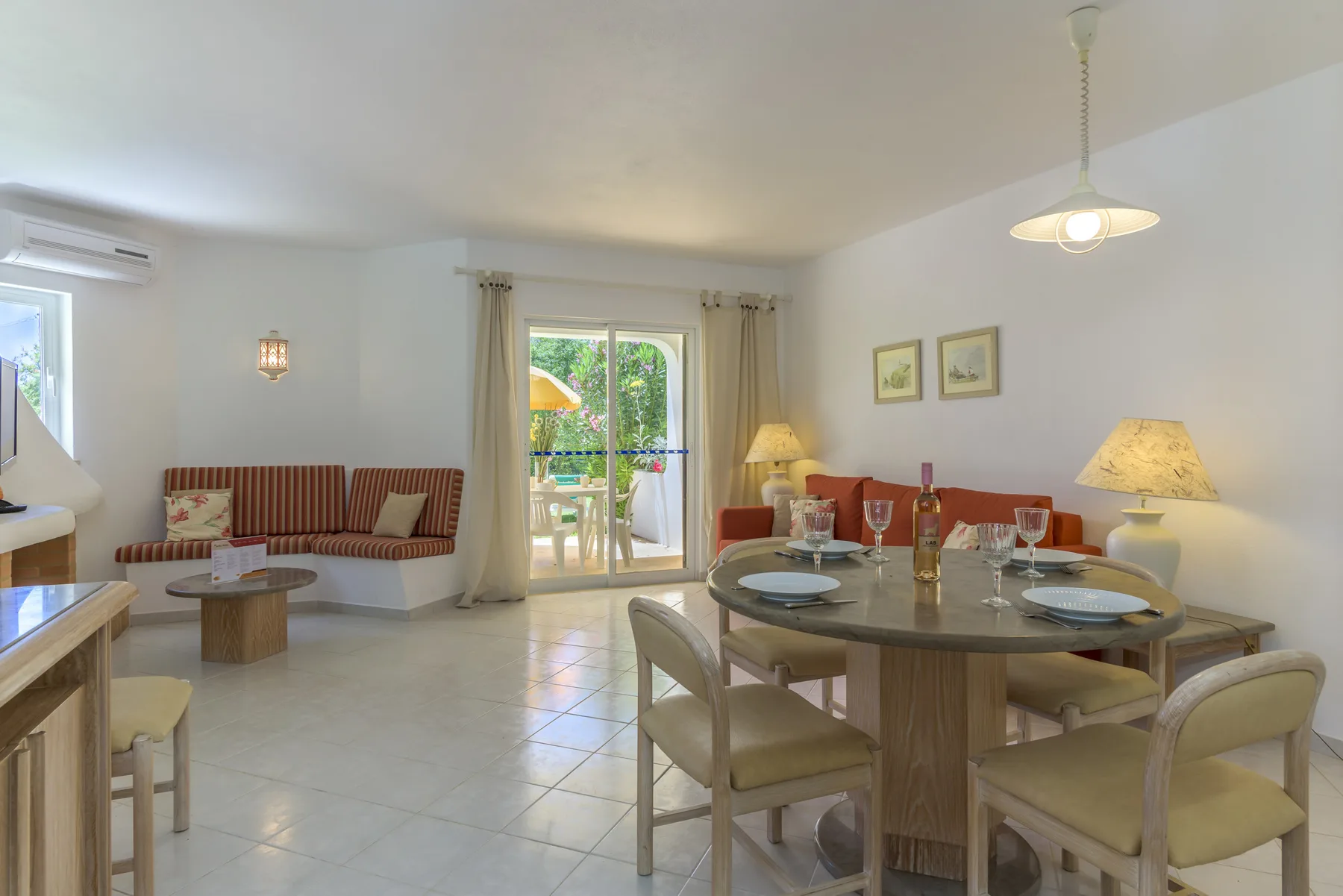 A bright dining and living area with a table, seating, and glass doors to a balcony.