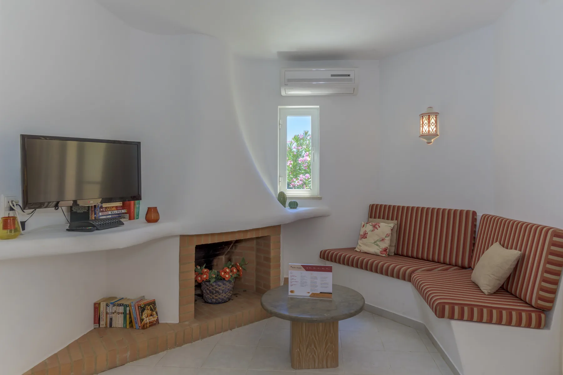 A living room with a television, built-in fireplace, and striped seating.