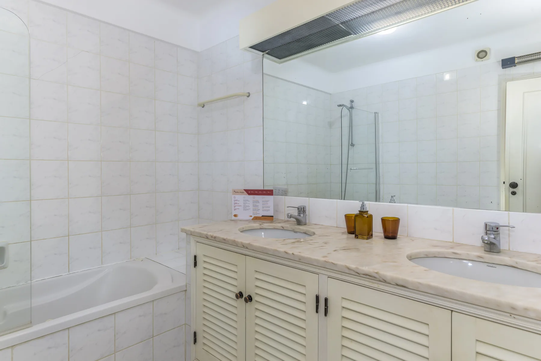 A tiled bathroom with a bathtub, vanity, and large mirror.