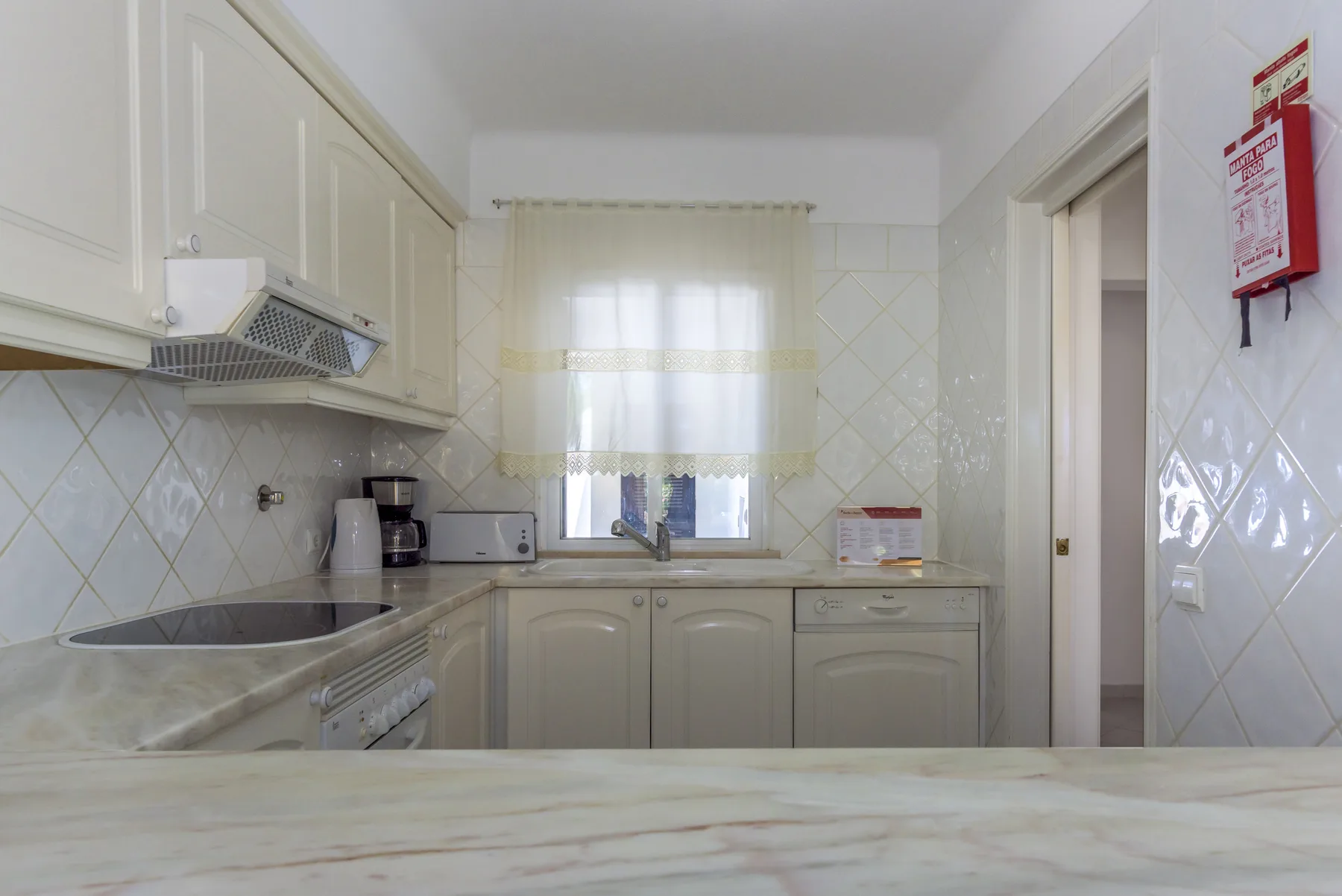 A bright kitchen with white cabinets, a countertop, and a window.