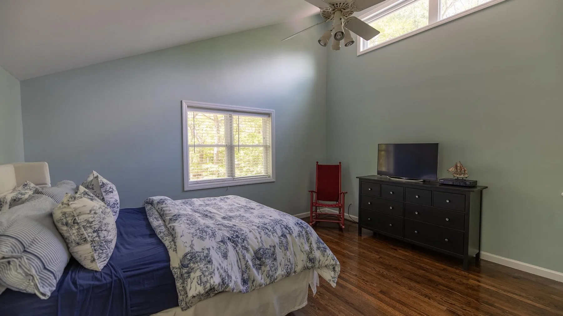 Un dormitorio con una cama, una cómoda y un televisor.