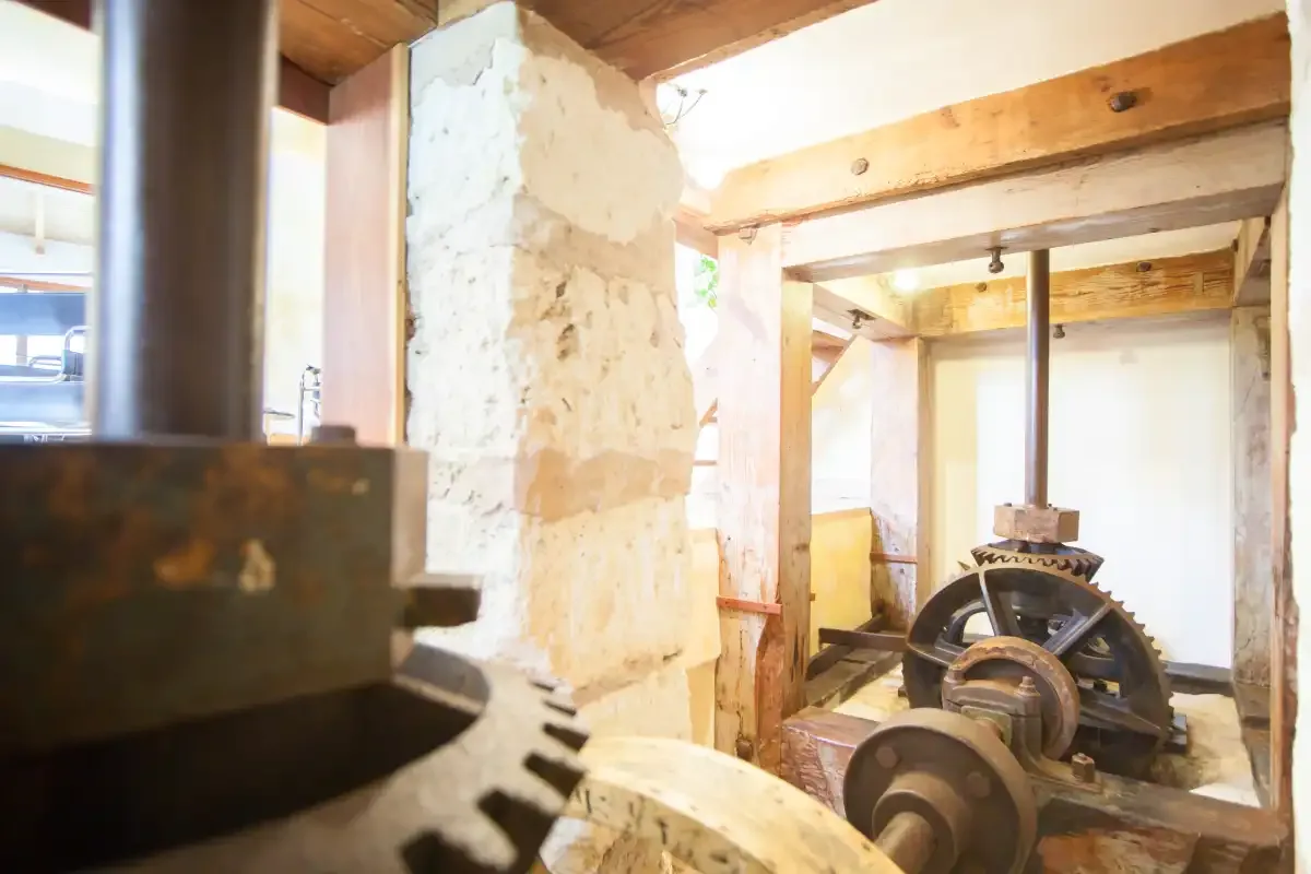 A rustic interior with exposed wooden beams and old mill machinery.